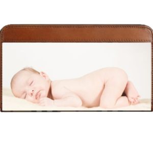 Baby sleeping photo on a white background in a brown leather wallet case, ideal for newborn photography props. The wallet features a transparent pocket.
