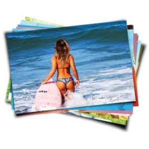 Bright woman carrying pink surfboard at the beach in a bikini, ocean waves behind, summer seaside scene.